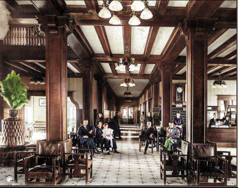 Guests seated in the lobby of the Great Southern Hotel, with carved oak columns, electric chandeliers and a tiled floor